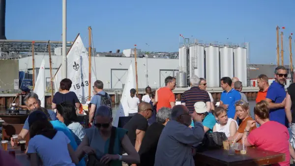 bezoekers doen een drankje op de redersdag, op de achtergrond zijn de vletten te zien